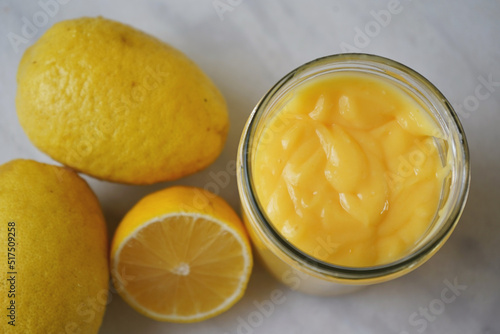 Lemon curd in a jar on a white marble table, flat lay