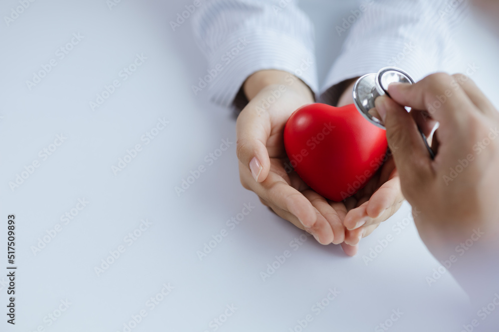 A doctor uses a stethoscope with a fake heart in the patient's hand, treating the disease from a medical professional and giving treatment on the spot. Concepts of medical treatment and specialists. A doctor uses a stethoscope with a fake heart in the patient's hand, treating the disease from a medical professional and giving treatment on the spot. Concepts of medical treatment and specialists.