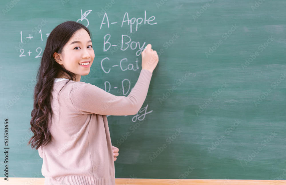 Portrait of smiling Asian teacher woman writing on chalkboard teach Portrait of smiling Asian teacher woman writing on chalkboard teach