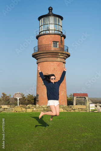 A chinese woman jumping in front of Gayhead lighthouse on Martha's Vineyard, Massachusetts photo