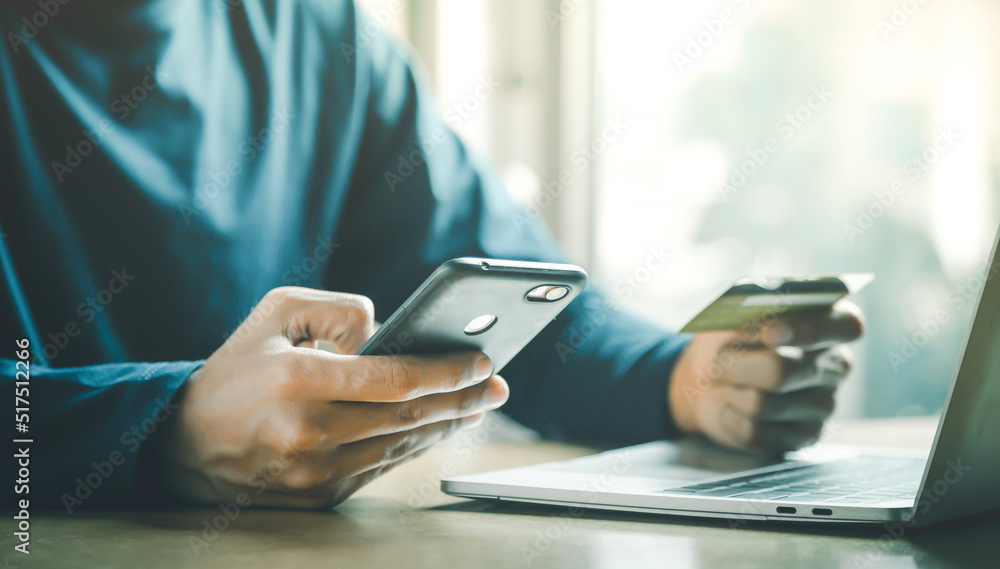 Man holding credit card and using smartphone at home online shopping ecommerce internet banking spend money work from home concept.