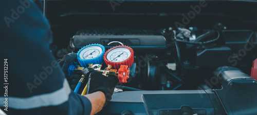 Close up hand of auto mechanic using measuring manifold gauge check the refrigerant and filling car air conditioner for fix and checking for repair service support maintenance and car insurance.