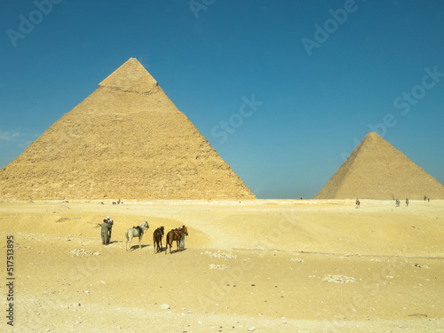 Small men in in front of great pyramids in Giza, Egypt