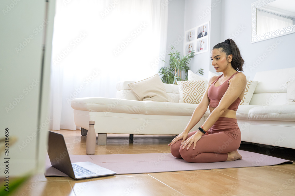 YOUNG GIRL DOING YOGA AND PILATES IN THE LIVING ROOM OF HER HOME WITH THE COMPUTER YOUNG GIRL DOING YOGA AND PILATES IN THE LIVING ROOM OF HER HOME WITH THE COMPUTER