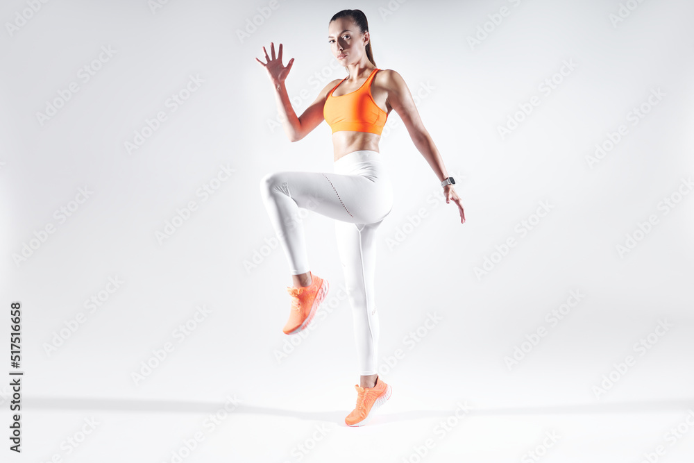 Fototapeta premium Beautiful young woman in sports clothing exercising against white background