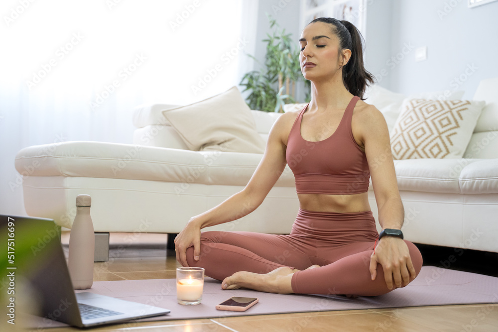 YOUNG GIRL DOING YOGA AND PILATES IN THE LIVING ROOM OF HER HOME WITH THE COMPUTER YOUNG GIRL DOING YOGA AND PILATES IN THE LIVING ROOM OF HER HOME WITH THE COMPUTER