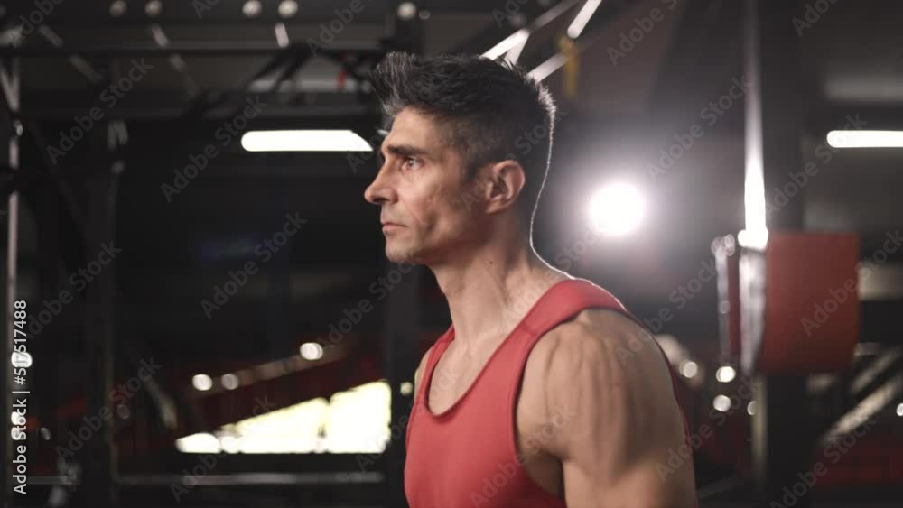 Close shot of Tough man standing in the gym and pumping his hands with dumbells
Close shot of Tough man standing in the gym and pumping his hands with dumbells