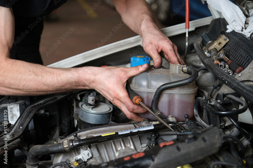 Car mechanic hands replacing antifreeze container. Mechanics workshop. Car mechanic hands replacing antifreeze container. Mechanics workshop.