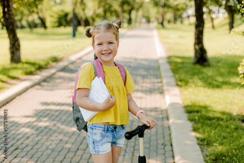 A beautiful little girl rides a scooter on her way back to school