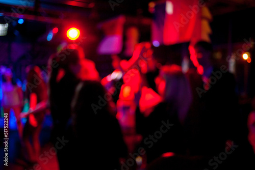 Silhouettes of dancing people in a club in front of bright scenic lights concept of disco, night life. Blurred people are dancing in a night club with original bokeh lights in the background.