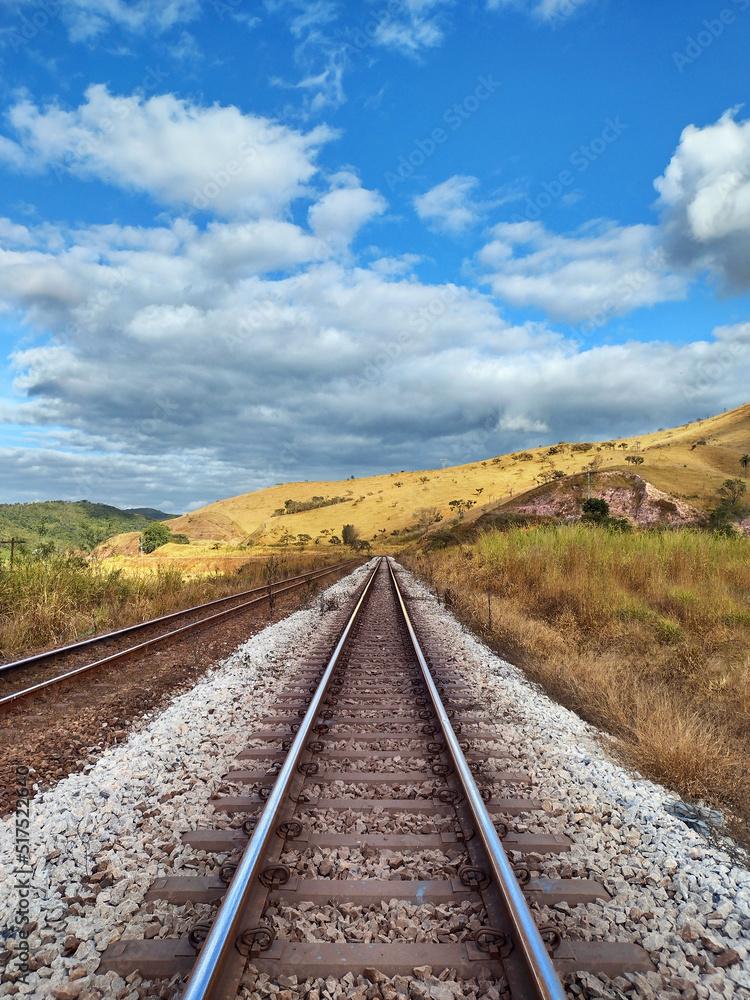 Railway train track , blue sky, clouds and mountains at Itabira Minas Gerais, Brazil Railway train track , blue sky, clouds and mountains at Itabira Minas Gerais, Brazil