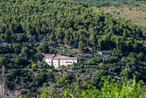 View from the top of mountain to the ancient building in the a picturesque valley surrounded by distinctly green trees and bushes in sunny summer day