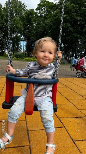 Wallpaper Mural Happy toddler sitting in a swing at the playground Torontodigital.ca