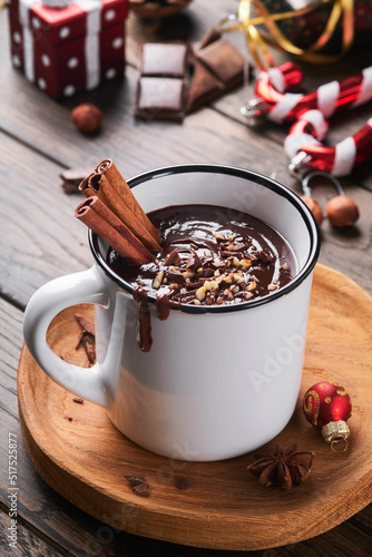 Hot chocolate. Homemade spicy hot chocolate with cinnamon, crushed hazelnut in enamel mug on old wooden background. Cozy seasonal holidays.