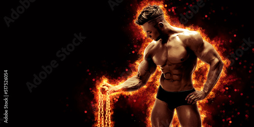 Body builder with fit torso belly chest and arms biceps triceps muscles holding chain while posing over the black background with fire. Bodybuilding concept 