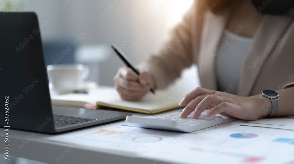 Close up Business woman using calculator and laptop for do math finance on wooden desk in office and business working background, tax, accounting, statistics and analytic research concept Close up Business woman using calculator and laptop for do math finance on wooden desk in office and business working background, tax, accounting, statistics and analytic research concept