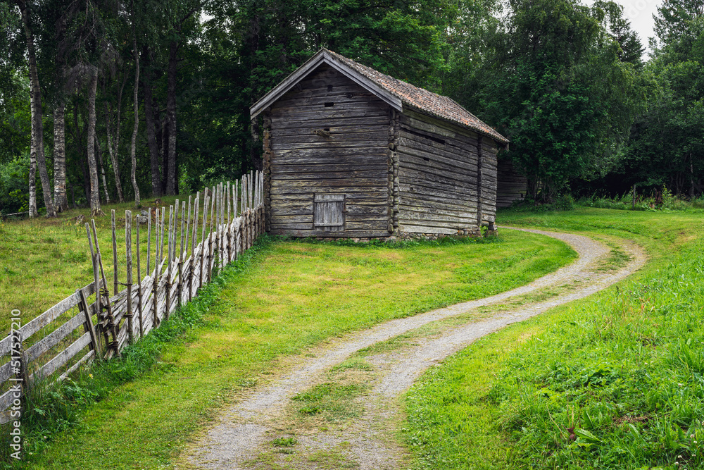 a curved gravel road passing by an old log house a curved gravel road passing by an old log house