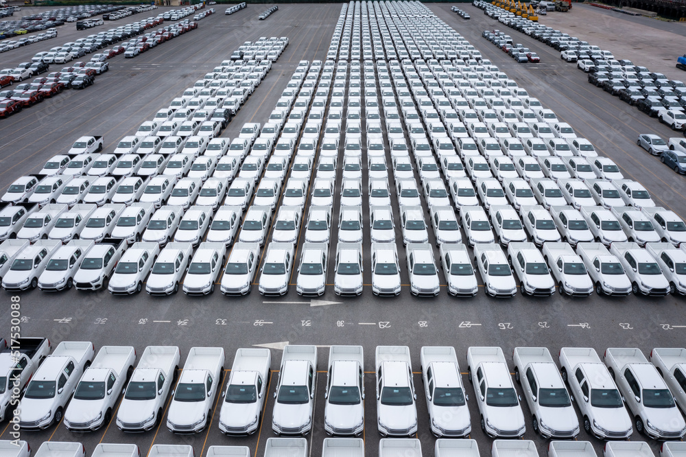 Fototapeta premium Aerial front view new cars lined up parked in a row in warehouse at the commercial dock for exporting to distributors and dealers international business logistics and transportation by container ship 