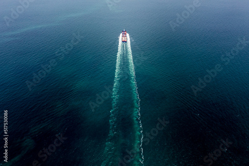 container cargo ship sailing full speed in pacific ocean to transport goods import export internationally or worldwide as business and industrial transport and marine services open sea aerial top view © SHUTTER DIN