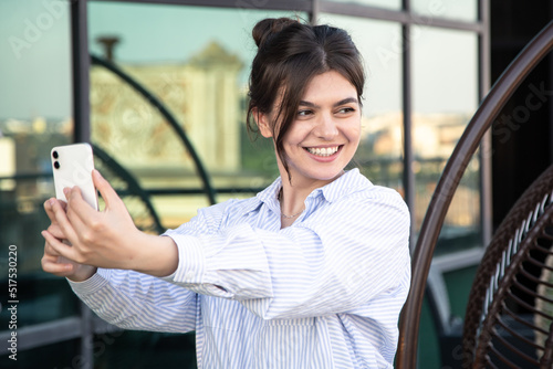 Smiling business young woman takes a selfie on a smartphone.