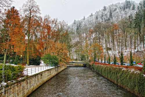 Karlovy Vary Czech Republic winter view with colored trees, snow covered hill and river in the middle photo