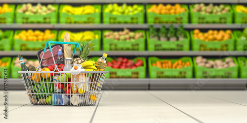 Shopping basket full of food in a grocery supermarket  or grocery store with shelves with fruits and vegetables.