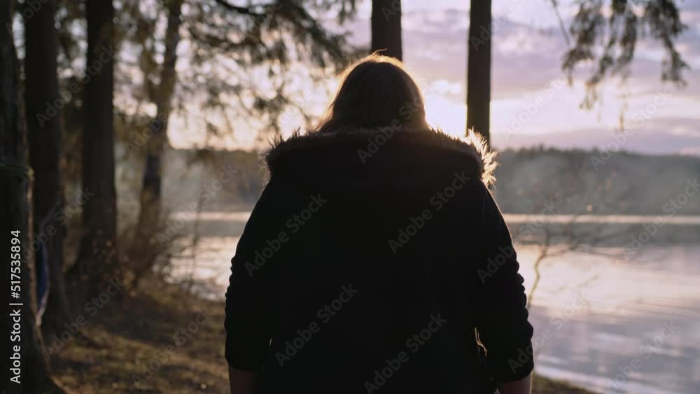 A woman walks along the river bank on a cold autumn day in the warm autumn sun. A woman walks along the river bank on a cold autumn day in the warm autumn sun.