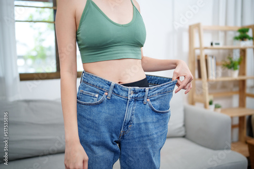 Slim woman wearing large jeans after diet, Successful weight loss concept.