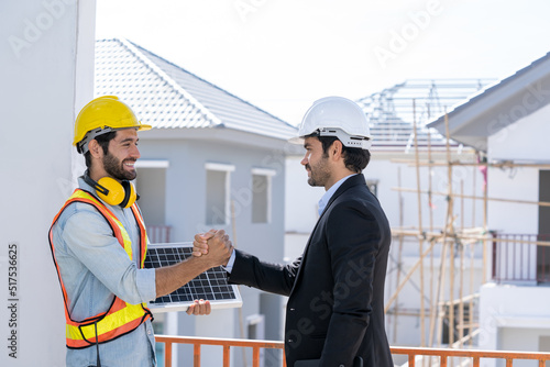 Close up businessman and engineers shaking hands after discussing install solar panels on houses under construction,Renewable energy for residential.