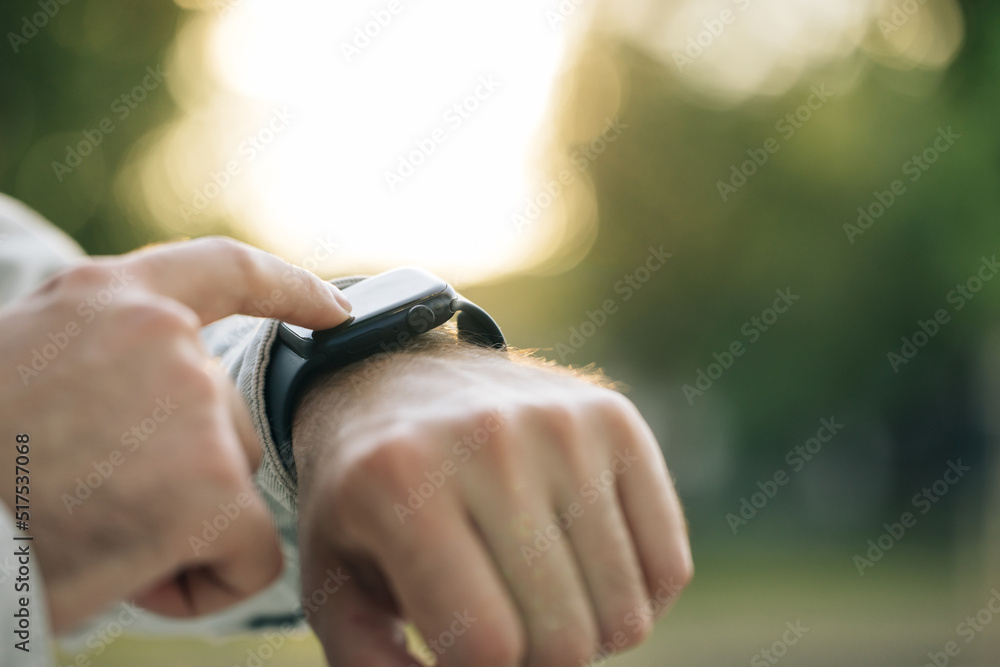 Smart watch. Smart watch on a man's hand outdoor. Man's hand touching a smartwatch. Close up shot of male's hand uses of wearable smart watch at outdoor in sunset