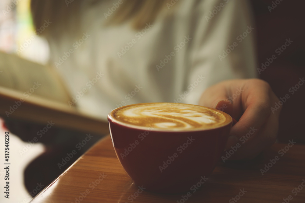 Woman with coffee reading book indoors, focus on cup Woman with coffee reading book indoors, focus on cup
