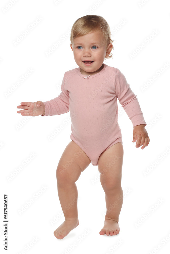 Cute baby girl in pink bodysuit learning to walk on white background Cute baby girl in pink bodysuit learning to walk on white background
