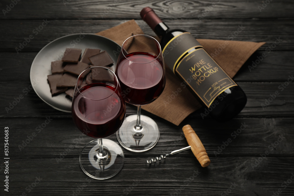 Composition with tasty red wine and chocolate on black wooden table