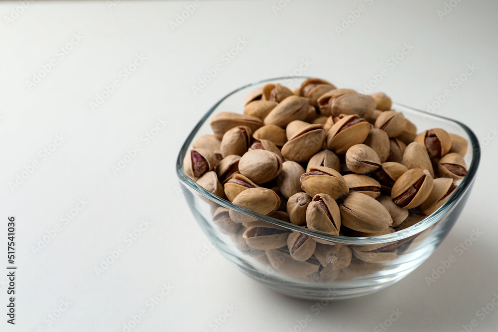 Bowl with pistachio nuts on white background, space for text Bowl with pistachio nuts on white background, space for text