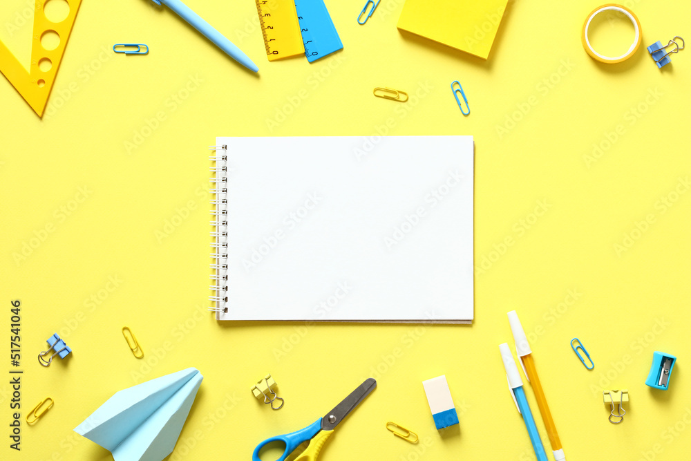 Back to school concept. Flat lay blank paper notepad with school stationery on yellow table. Top view. Back to school concept. Flat lay blank paper notepad with school stationery on yellow table. Top view.