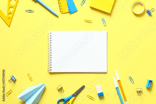 Back to school concept. Flat lay blank paper notepad with school stationery on yellow table. Top view.
