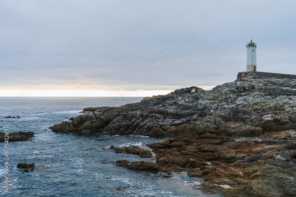 Lighthouse in rocky coast on a cloudy day