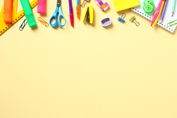 Flat lay colorful school stationery on yellow table. Top view. Frame border made of office supplies. Back to school concept.
