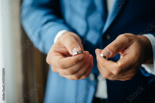 wedding rings in the hands of the groom, the groom in a blue suit