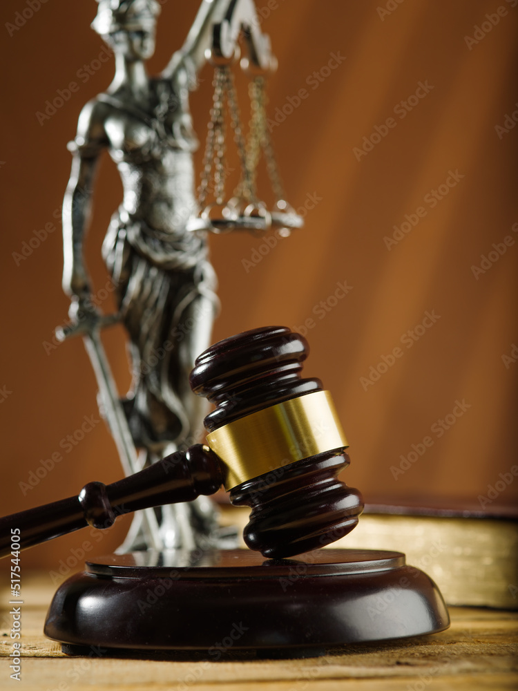 Close-up. Symbols of a fair, honest American court. Wooden gavel of the judge, sculpture of Themis and an open book on a beige background. Judgment and Justice. Close-up. Symbols of a fair, honest American court. Wooden gavel of the judge, sculpture of Themis and an open book on a beige background. Judgment and Justice.