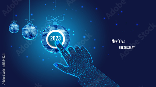 Startup concept. New Year fresh start. 2023 on the button. Polygonal hand. Clicking. Polygonal Christmas balls. Background of the blue starry sky.