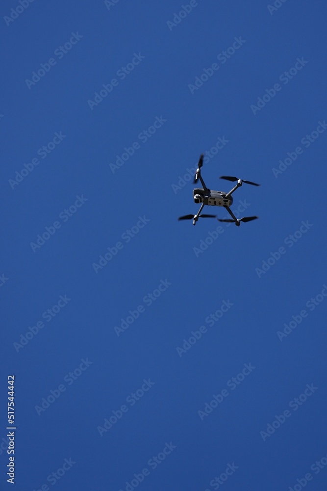 A drone flys overhead against a blue sky. A drone flys overhead against a blue sky.