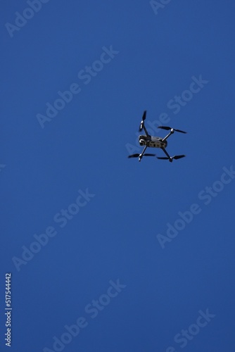 Fototapeta Naklejka Na Ścianę i Meble -  A drone flys overhead against a blue sky.