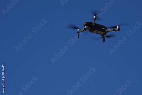 Fototapeta Naklejka Na Ścianę i Meble -  A drone flys overhead against a blue sky.