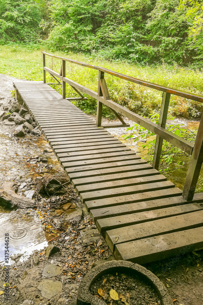 Simple wooden footbridge to cross a stream at a hiking trail in germany Simple wooden footbridge to cross a stream at a hiking trail in germany