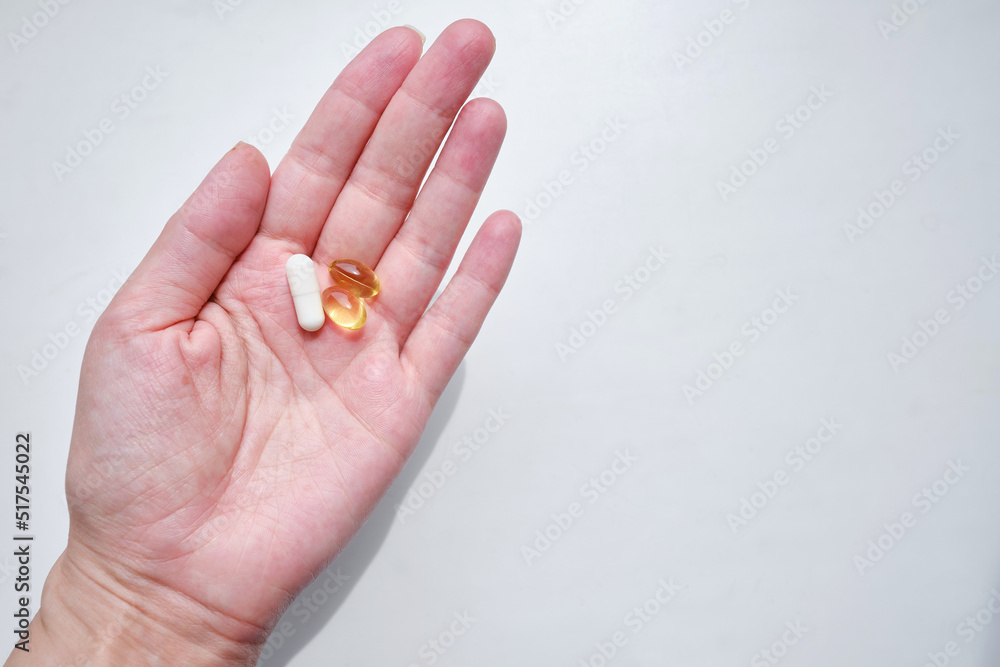Pill close-up on a white background in a hand. Taking vitamins or medications. The concept of healthcare, medicine, pharmacies, disease prevention Pill close-up on a white background in a hand. Taking vitamins or medications. The concept of healthcare, medicine, pharmacies, disease prevention