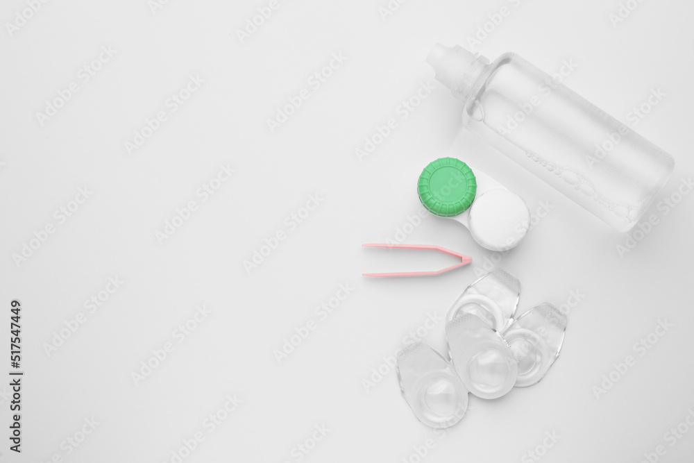 Naklejka premium Packages with contact lenses, case, tweezers and drops on white background, flat lay. Space for text