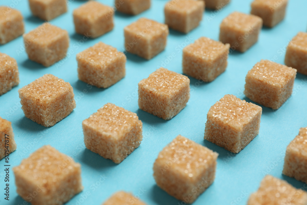 Brown sugar cubes on turquoise background, closeup Brown sugar cubes on turquoise background, closeup