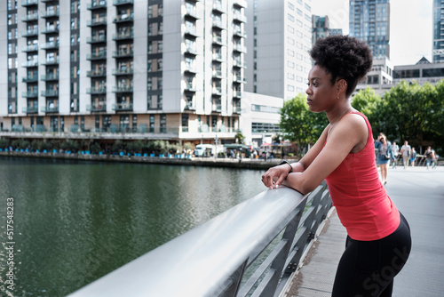 Portrait of young sport black woman leaning on a banister on a river. © Jorge Elizaquibel