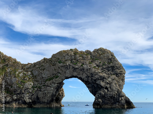 Hot summer day at Durdle Door limestone arch on the Jurassic Coast in Dorset. Natural landmark.Summer holidays England. Crowded beach, people are spending summer weekend in English seaside. Pure clean